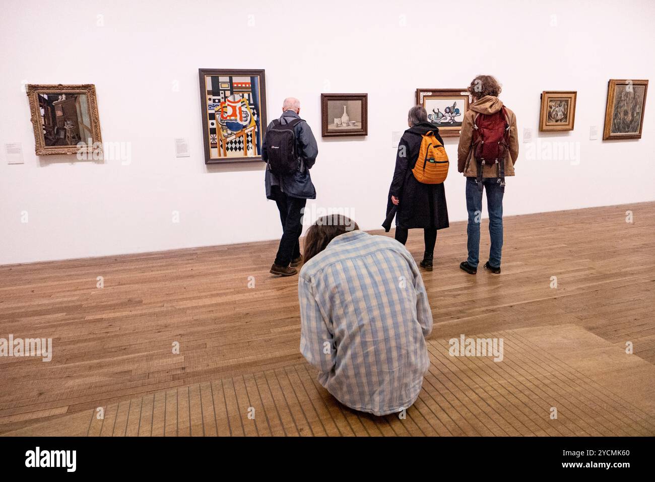 Ein Mann sitzt, während die Leute Kunstwerke im Tate Modern in London, England betrachten. Foto: SMP News Stockfoto