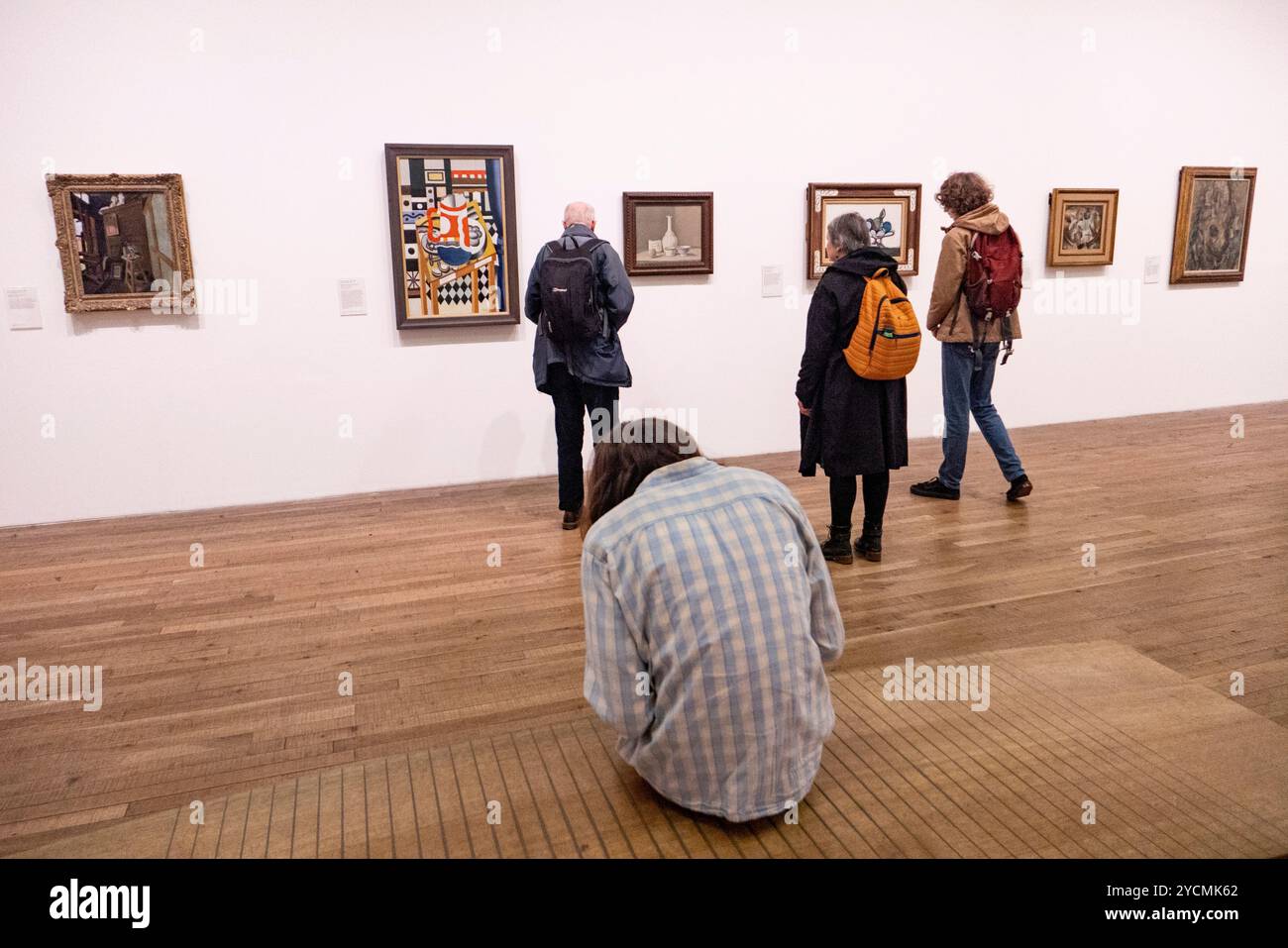 Ein Mann sitzt, während die Leute Kunstwerke im Tate Modern in London, England betrachten. Foto: SMP News Stockfoto