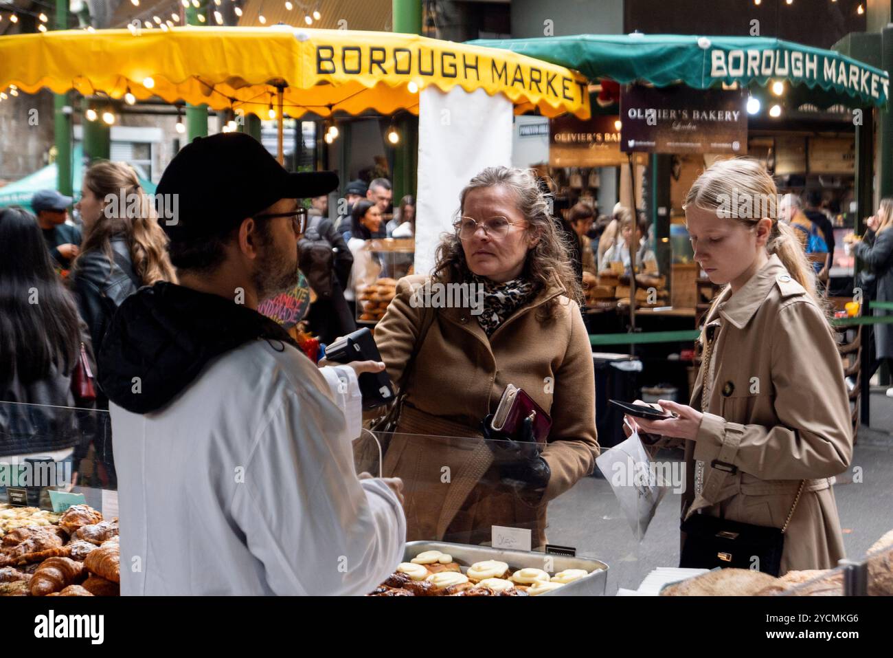 Eine Dame zahlt am 23. Oktober 2024 mit dem Handy für Waren auf dem Borough Market, London, England. Foto: SMP News Stockfoto