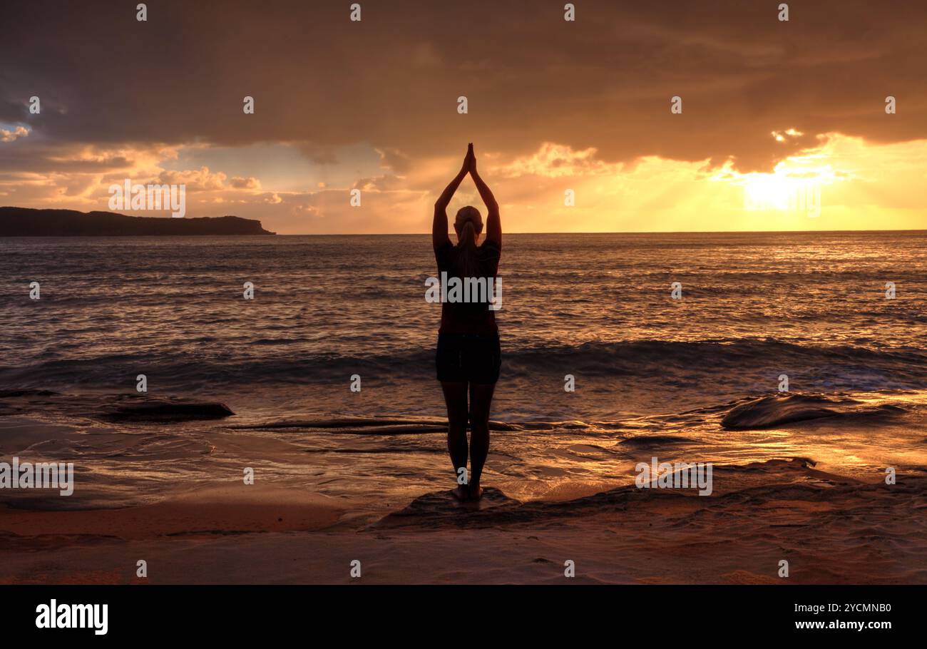Woman Tadasana - Yoga in Bergposition am Meer bei Sonnenaufgang Stockfoto