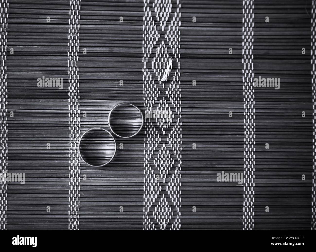 Zwei Trauringe auf Bambusmatte Stockfoto