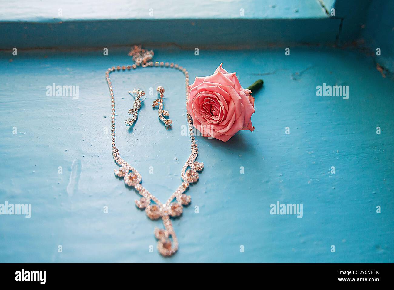 Elegante Rose mit Halskette und Ohrringen auf einem Blau Stockfoto