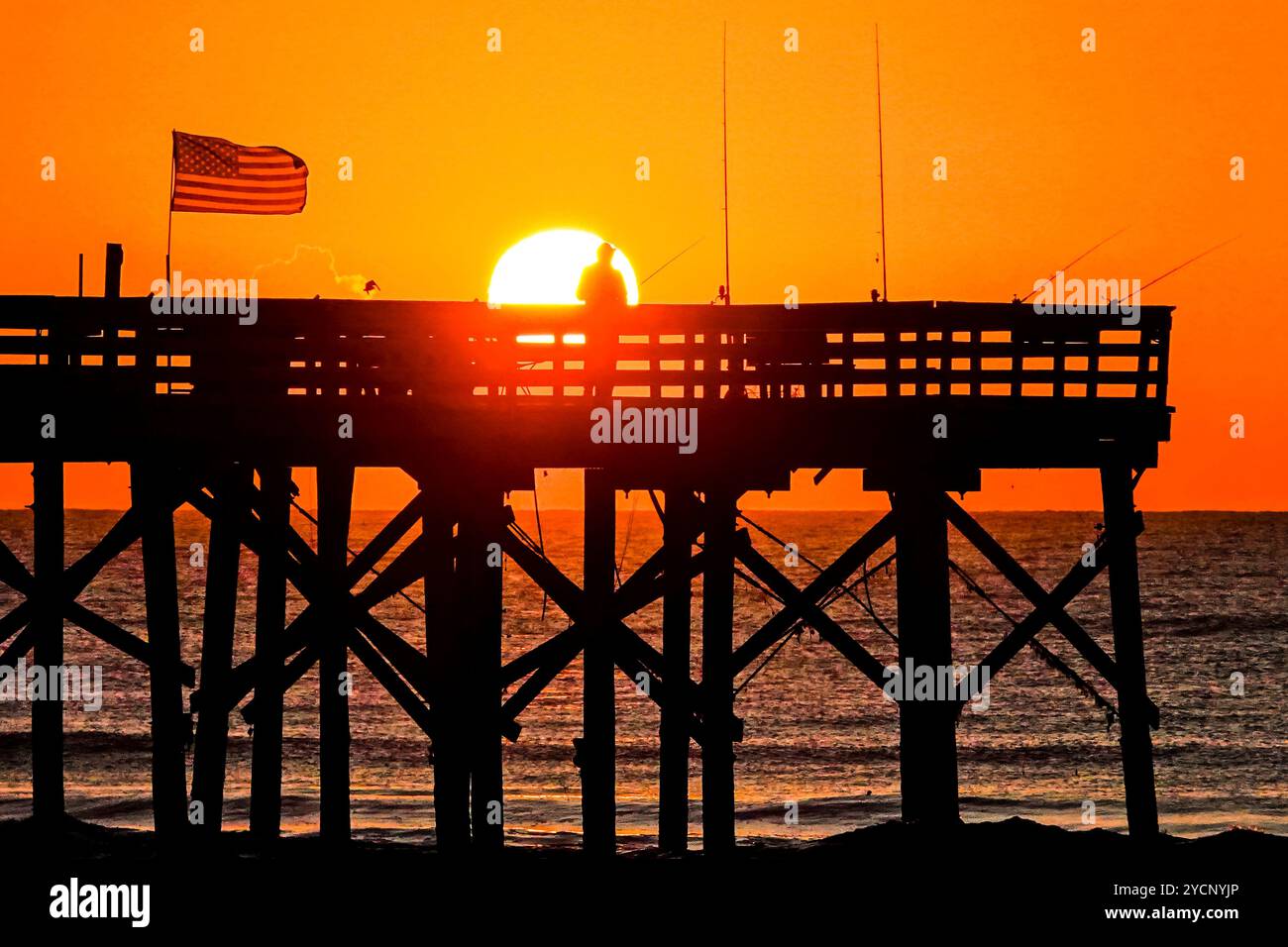 Isle Of Palms, Usa. Oktober 2024. Fisherman Silhouetten bei einem dramatischen Sonnenaufgang am Isle of Palms Pier, 23. Oktober 2024 in Isle of Palms, South Carolina. Sonniges und warmes Wetter wird für die nächsten Wochen vorhergesagt. Quelle: Richard Ellis/Richard Ellis/Alamy Live News Stockfoto