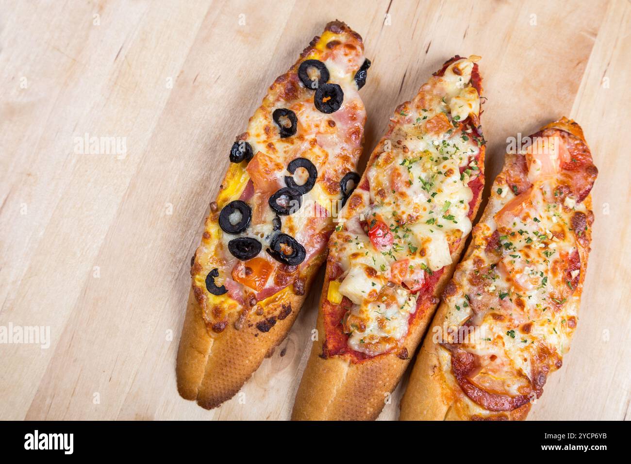 Assorti Bruscjetta mit Wurst, Käse, Tomaten aus großem weißem Baguette auf hölzernem Hintergrund Stockfoto