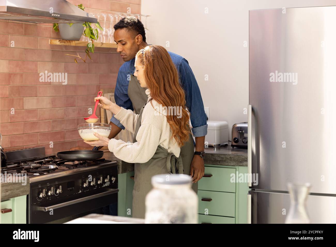 Multirassische Paare kochen zusammen in der Küche, bereiten Feiertagsessen mit Freude zu, zu Hause Stockfoto