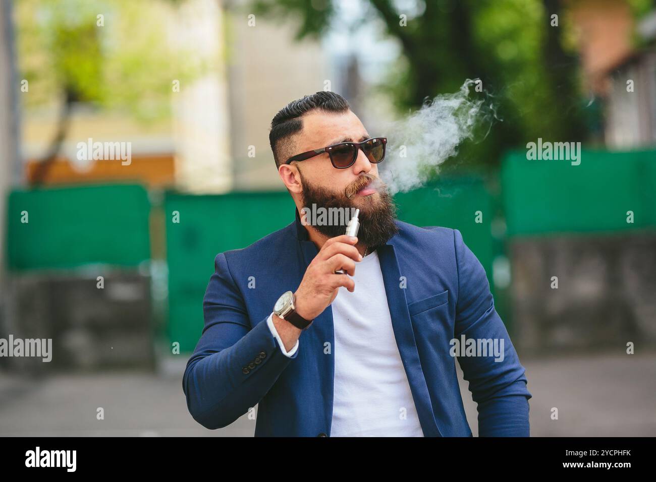 Gut gekleideter Mann, der elektronische Zigaretten raucht Stockfoto