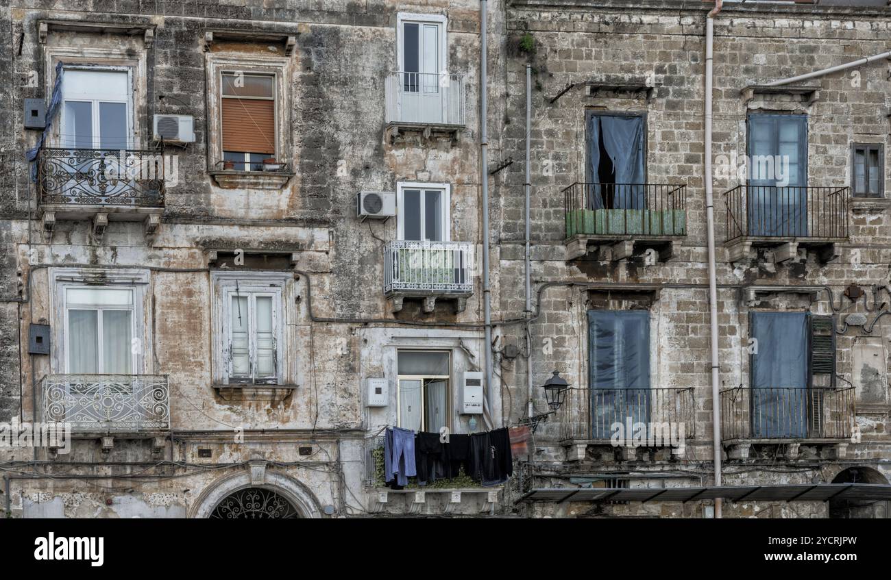 Taranto, Italien, 30. November 2023: Schäbige, schicke, verfallene Gebäude mit Waschküche, die von den Balkonen hängen, in der Altstadt von Tarent, Europa Stockfoto