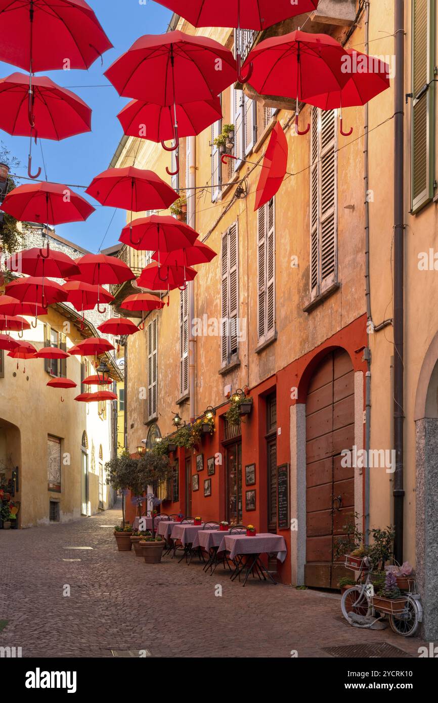 Luino, Italien, 16. März 2023: Vertikaler Blick auf eine Kopfsteinpflasterstraße mit kleinen Geschäften und farbenfrohen Dekorationen in der Altstadt von Luino, Europa Stockfoto