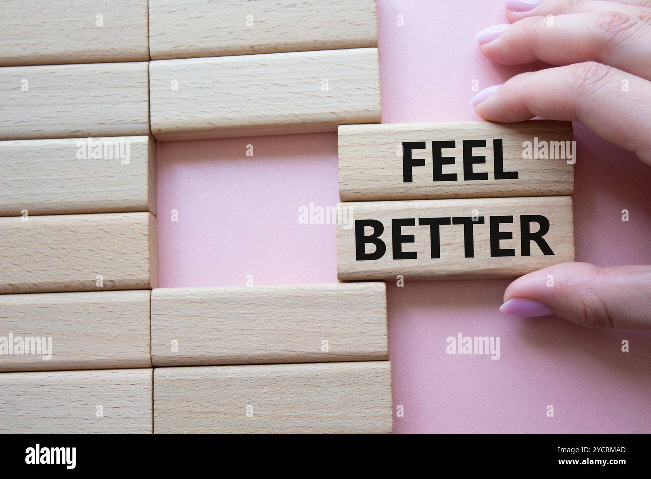 Das Symbol „Feel better“. Holzblöcke mit Worten fühlen sich besser an. Geschäftsmann Hand. Schöner rosafarbener Hintergrund. Business and Feel Better Konzept. Kopierbereich. Stockfoto