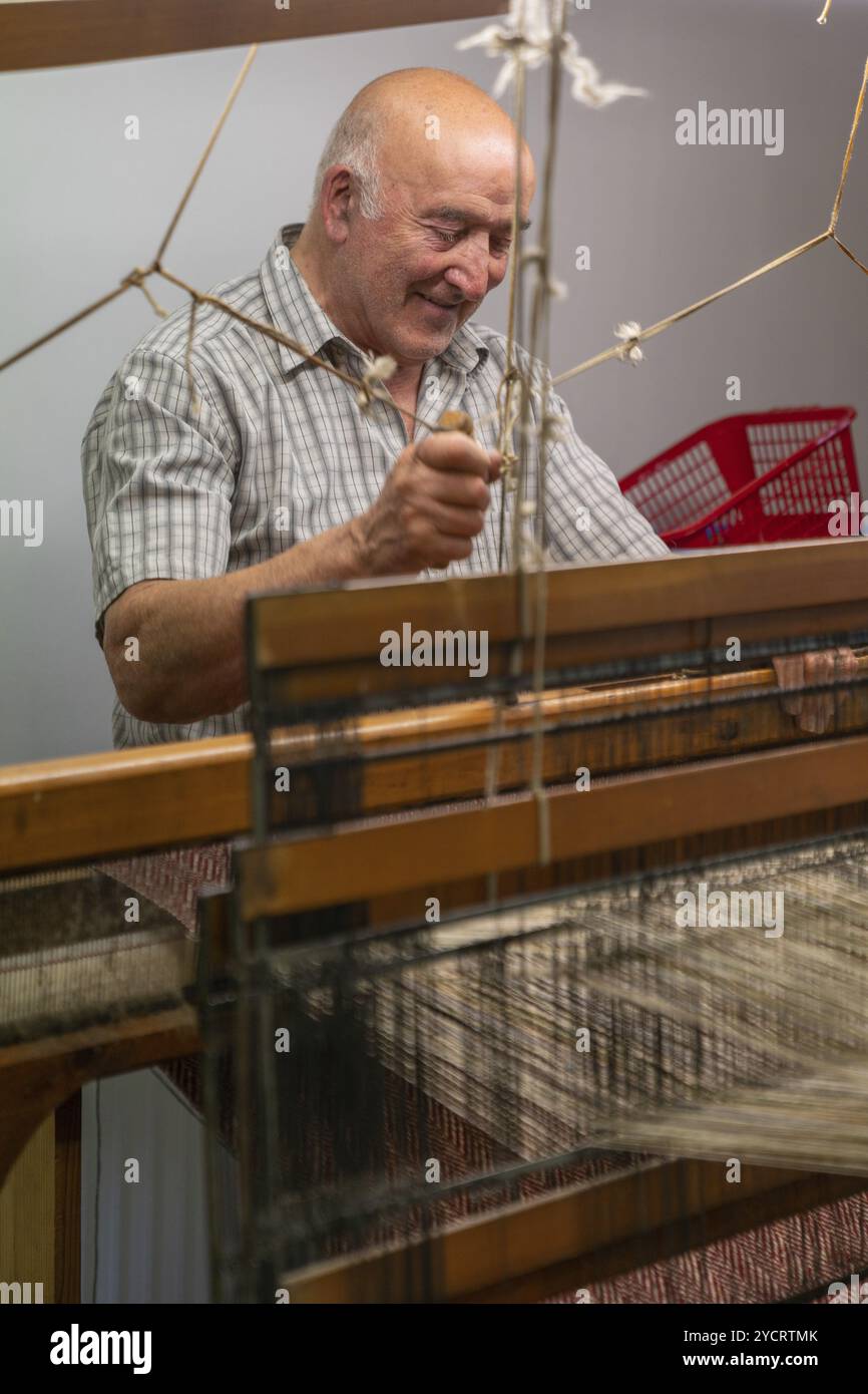 Ardara, Irland, 13. Juli 2022: Meister, der an einem traditionellen Holzwebstuhl arbeitet und handwebt, Wolle mit Fischgrätmuster, Europa Stockfoto