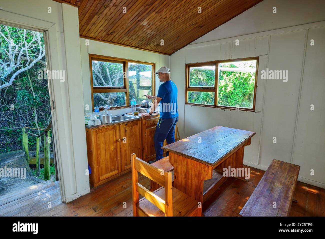 Mann, der in der Küche einer Selbstversorger-Hütte auf dem Alexandria Wanderweg, Woody Cape Hut, Addo Elephant National Park, Eastern Cape, Südafrika arbeitet Stockfoto