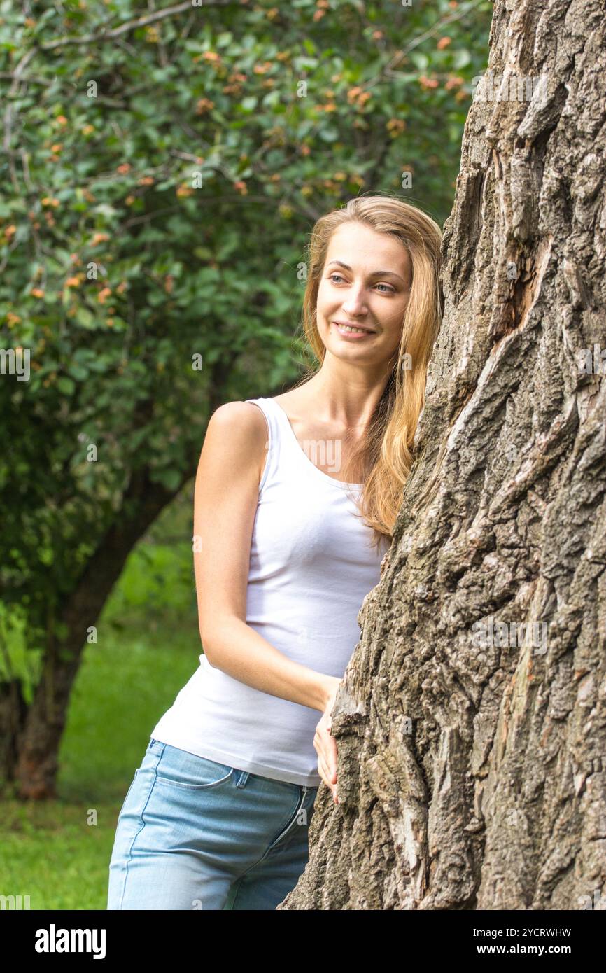 Nahaufnahme nachdenkliche junge Naturliebhaberin, die einen riesigen Baum umarmt Stockfoto