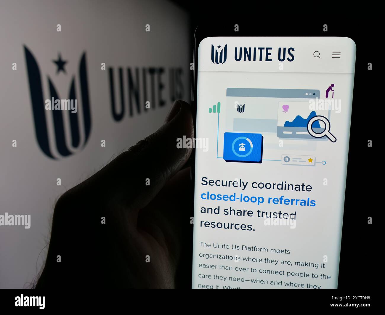 Person, die ein Mobiltelefon hält, mit der Webseite des Sozialunternehmens Unite USA Inc. (Unite US) auf dem Bildschirm mit Logo angezeigt wird. Konzentrieren Sie sich auf die Mitte des Telefondisplays. Stockfoto