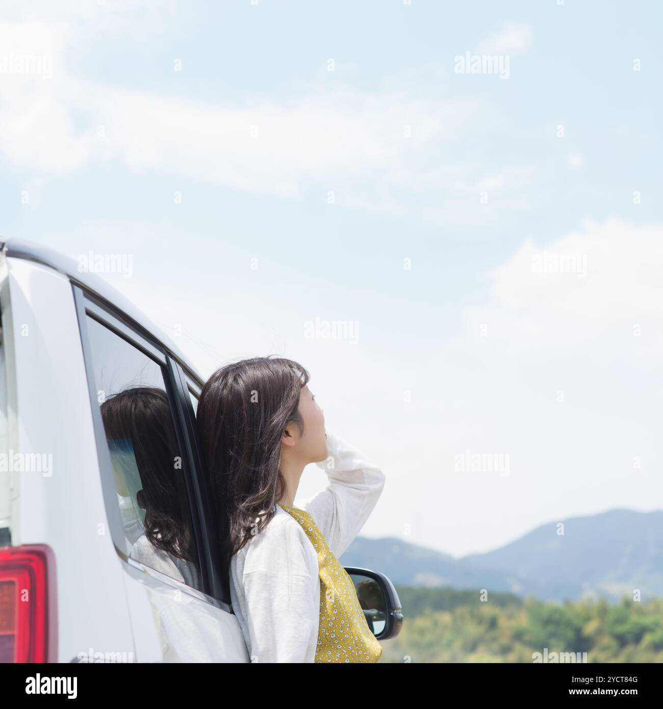 Frau, die sich gegen das Auto lehnt und in den Himmel blickt Stockfoto