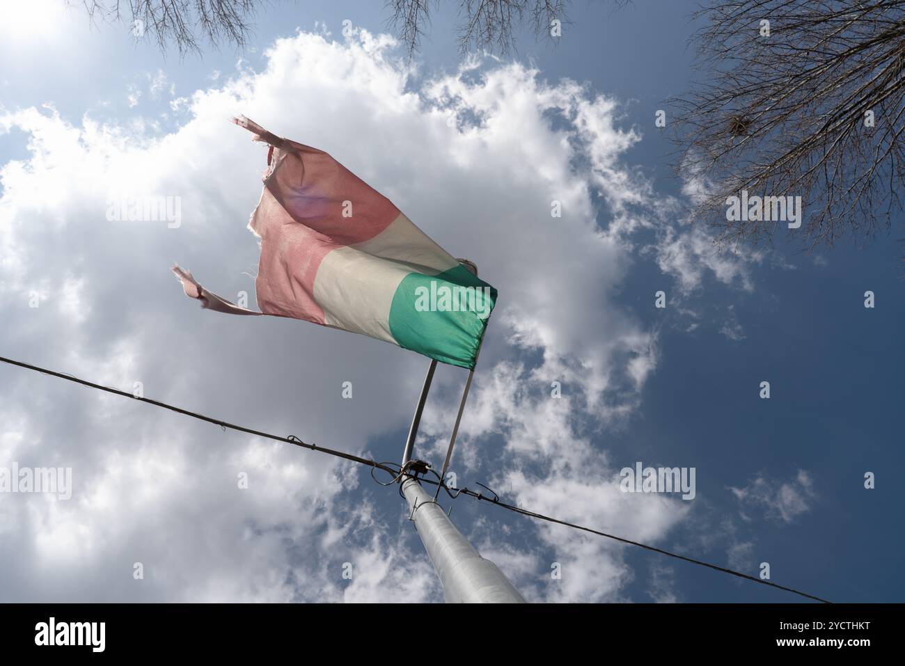 Alte und ruinierte italienische Flagge vor einem bewölkten Himmel Stockfoto