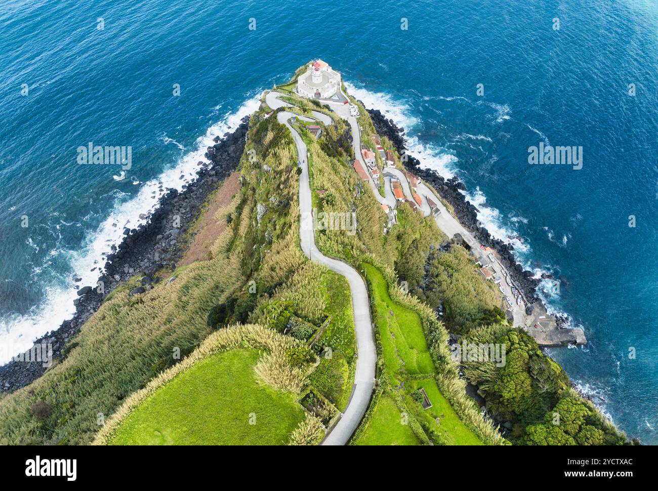 Aus der Vogelperspektive einer kurvigen Straße, die zu einem Leuchtturm auf den Azoren führt (Farol da Ponta do Arnel ) Stockfoto