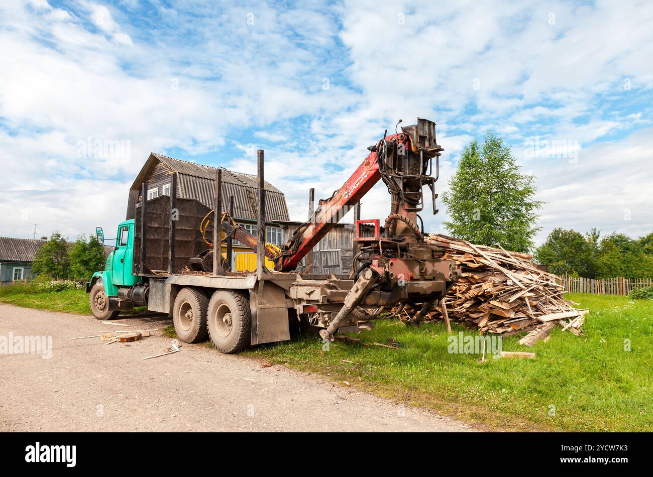 Baumstamm-hydraulischer Manipulator entlädt am Sommertag Holz vom Lkw Stockfoto