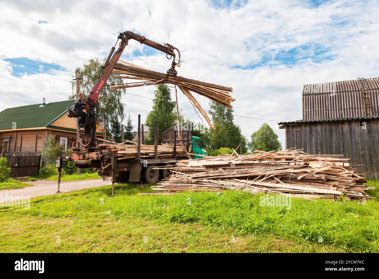 Baumstamm-hydraulischer Manipulator entlädt am Sommertag Holz vom Lkw Stockfoto