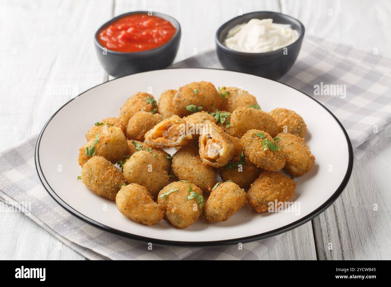 Frittierte panierte Muscheln, serviert mit Mayonnaise und Ketchup in Nahaufnahme auf einem Teller auf einem Tisch. Horizontal Stockfoto