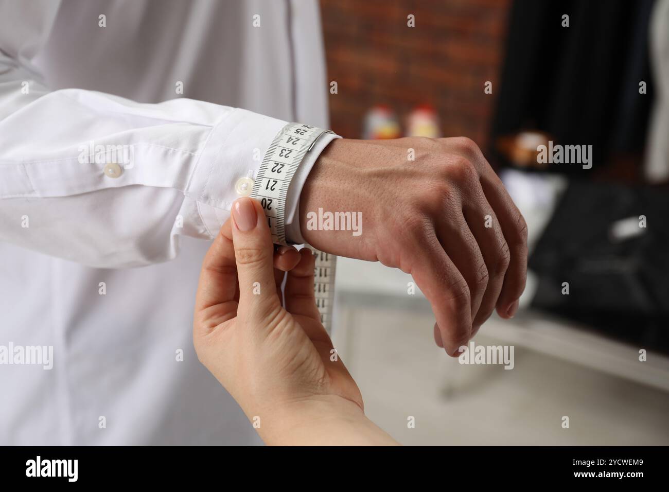 Professioneller Schneider zur Messung des Handgelenkumfangs des Kunden im Atelier, Nahaufnahme Stockfoto