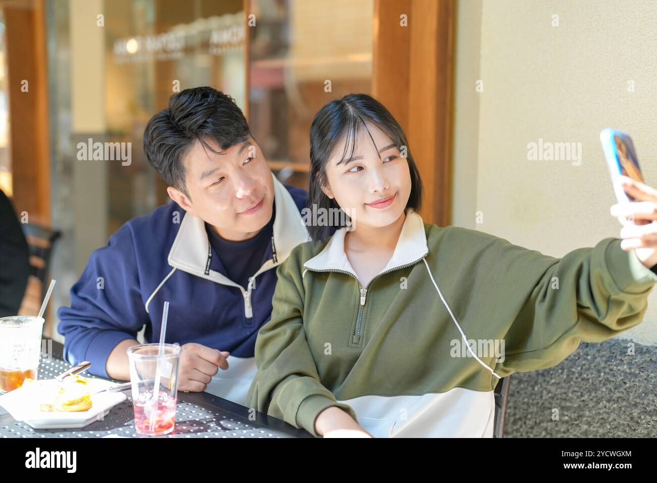 Ein Paar, ein koreanischer Mann in den 30ern und eine Frau in den 20ern, trägt Trainingsanzüge und genießt einen Nachmittag in einem netten Café im westlichen Stil in Seoul, Südkorea. Stockfoto