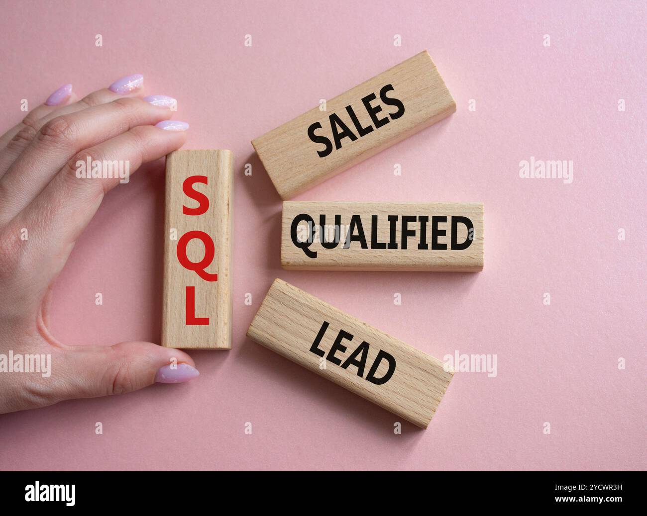 SQL - qualifizierter Lead für Vertrieb. Holzwürfel mit SQL-Wörtern. Geschäftsmann Hand. Schöner rosafarbener Hintergrund. Business- und SQL-Konzept. Kopierbereich. Stockfoto