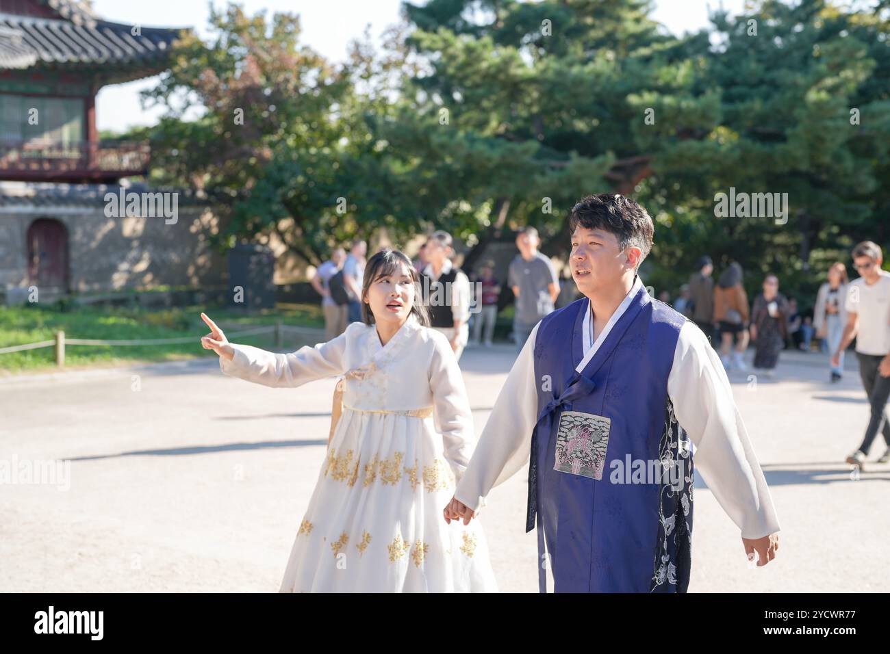 Ein koreanisches Paar, ein Mann in den 30ern und eine Frau in den 20ern, geht harmonisch durch ein historisches Gebäude in Seoul, Südkorea, mit Hanbok. Stockfoto