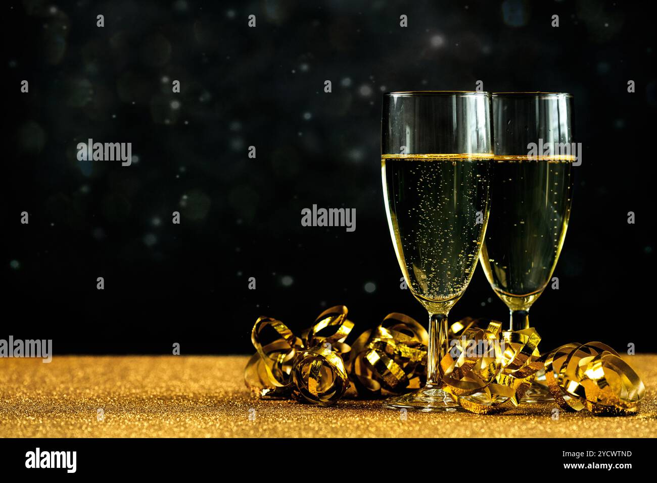 Frohes neues Jahr. Sektgläser mit goldenen Schnürern und Platz für Text auf einem goldenen Tisch. Hintergrund für Silvesterfeier Stockfoto