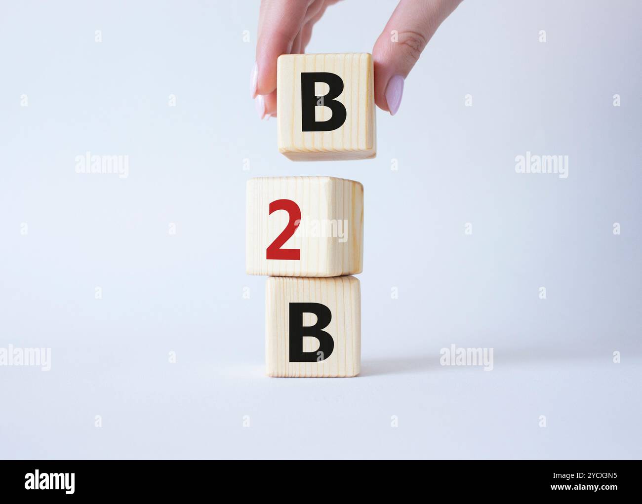 B2B, Business-to-Business-Marketing-Symbol. Konzeptwort B2B auf Holzblöcken. Schöner weißer Hintergrund. Geschäftsmann Hand. Business- und B2B-Konzept. Stockfoto