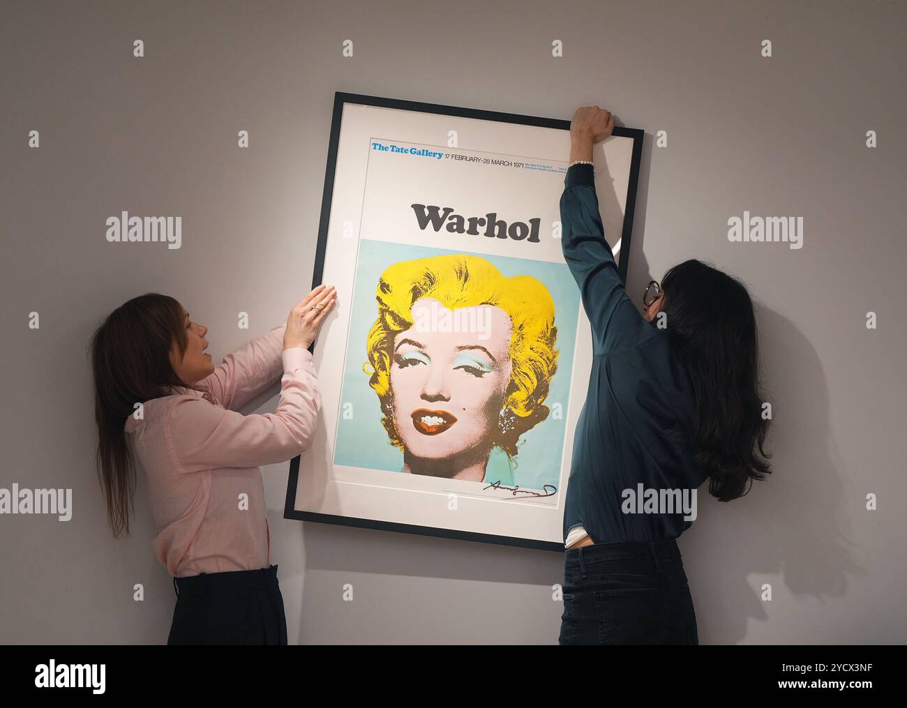 Mitglieder der Galerie positionieren ein signiertes Tate Gallery Poster von Andy Warhol, Marilyn Monroe, 1971, während eines Fotobesuchs in der neuen Galerie Shapero Modern in London, für ihre erste Ausstellung, The Modern Muse, mit berühmten Werken von Andy Warhol, David Hockney, Picasso, Grayson Perry und Banksy, die Kate Moss darstellen, mit den Haaren und dem charakteristischen Schönheitsfleck von Marilyn Monroe. Bilddatum: Donnerstag, 24. Oktober 2024. Stockfoto