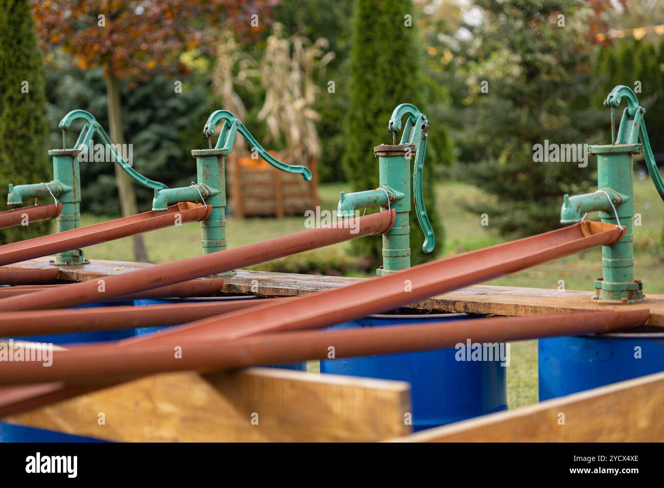 Alte Handwasserpumpen aus Metall im Outdoor Park an einem sonnigen Tag. Konzept traditioneller Wassersysteme, ländliches Leben und Vintage-Maschinen Stockfoto