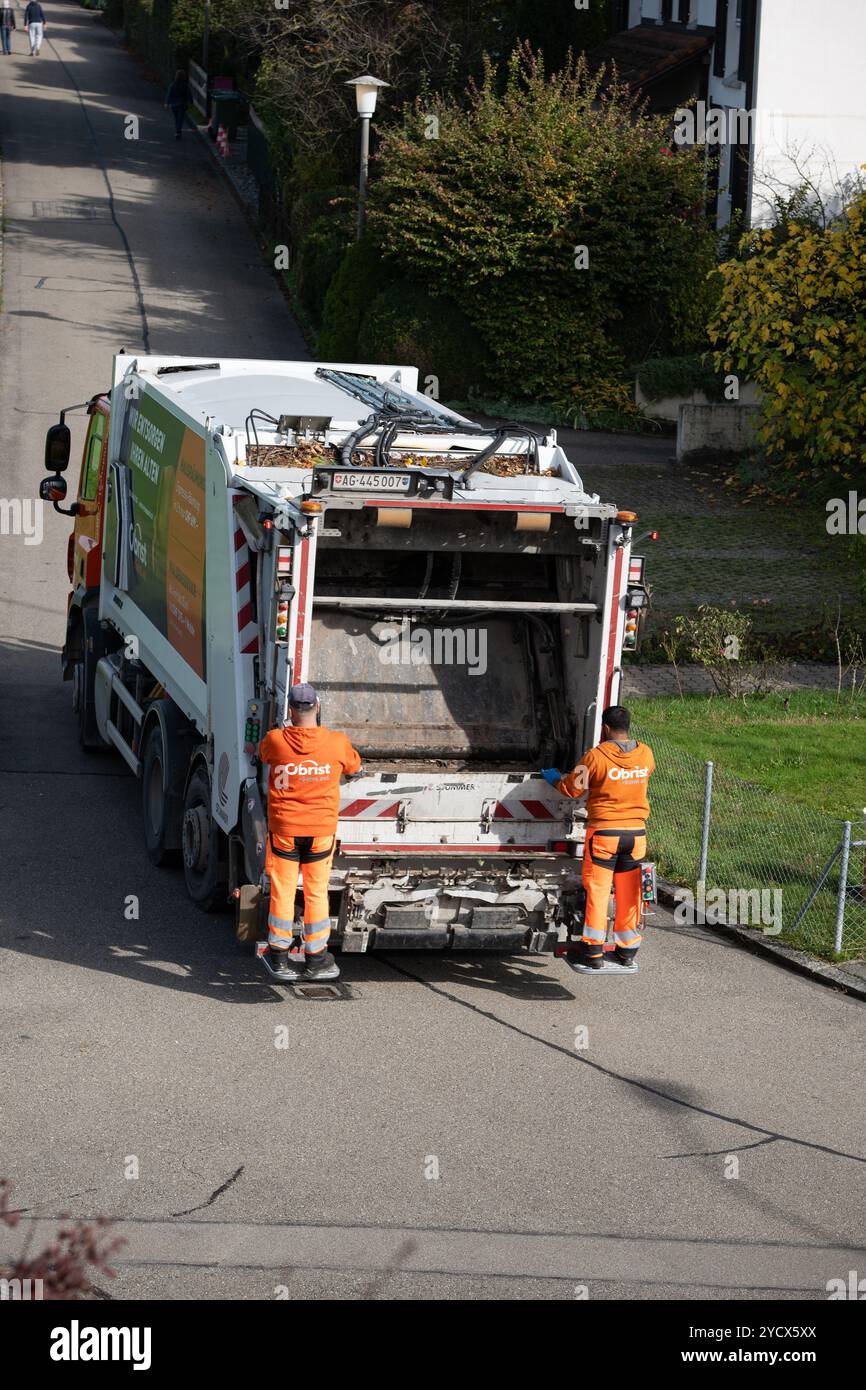 17-10-2024, Urdorf, Kanton Zürich, Schweiz. Zwei Müllsammler in Uniformen, die auf dem Rücksitz eines Müllwagens in Urdorf fahren. Nicht Erkannt Stockfoto