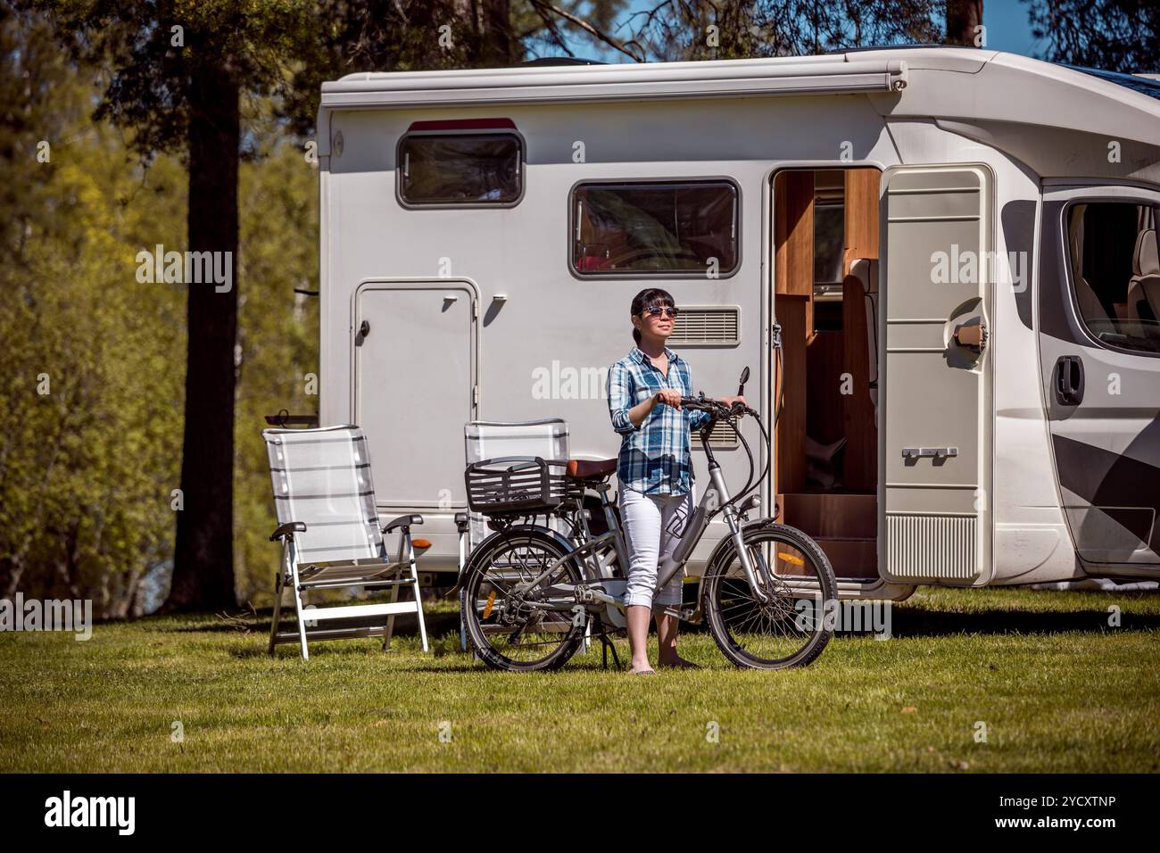 Frau auf dem Elektrofahrrad, die auf dem Campingplatz ausruht, VR Caravan Car Vacation. Stockfoto