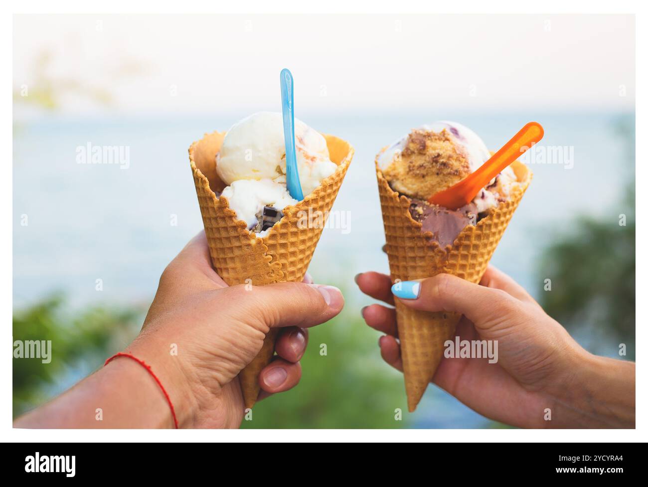 Schönes helles Eis mit verschiedenen Geschmacksrichtungen in den Händen von ein paar Stockfoto