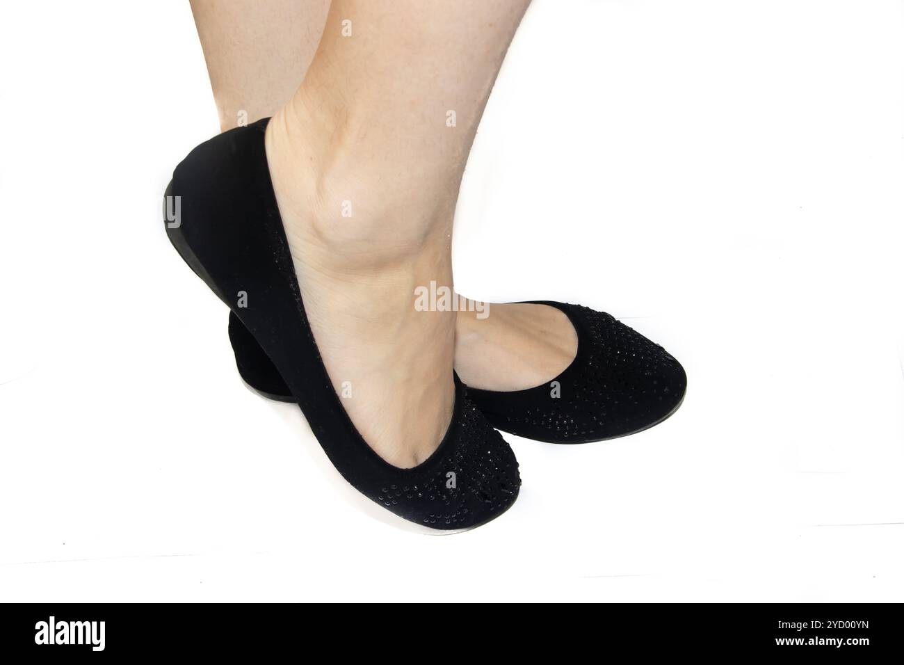 Schwarze Ballettflaches auf weiblichen Beinen auf weißem Hintergrund. Sommerschuhe für Damen. Schwarze Ballerinas auf weißem Hintergras Stockfoto