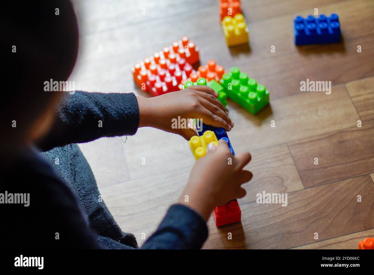 Bunte Kunststoffbausteine auf einem Holzboden, die einen Moment der Kreativität und des Spiels mit lebhaften Farben zeigen Stockfoto