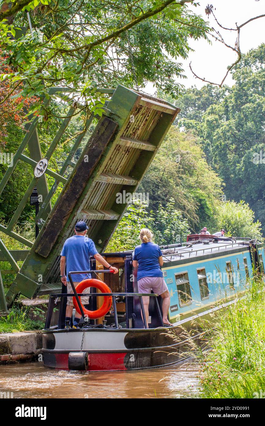 Ein Mann, der ein Schmalboot über eine Liftbrücke auf dem Llangollenkanal bei Whixall Moss bei Whitchurch Shropshire England steuert Stockfoto