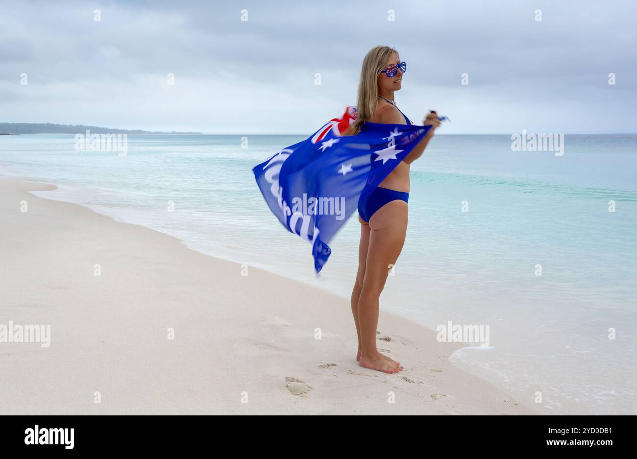 Weiblich am Strand mit australischer Flagge im Wind Stockfoto