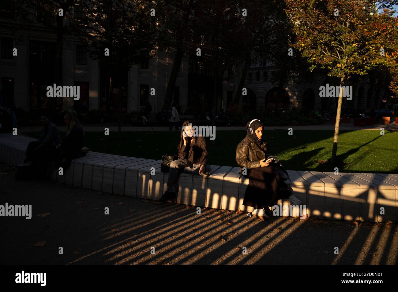 Die Studenten sitzen vor dem Kings College London am Strand in der Hauptstadt und genießen das Herbstabendlicht in England, Großbritannien Stockfoto