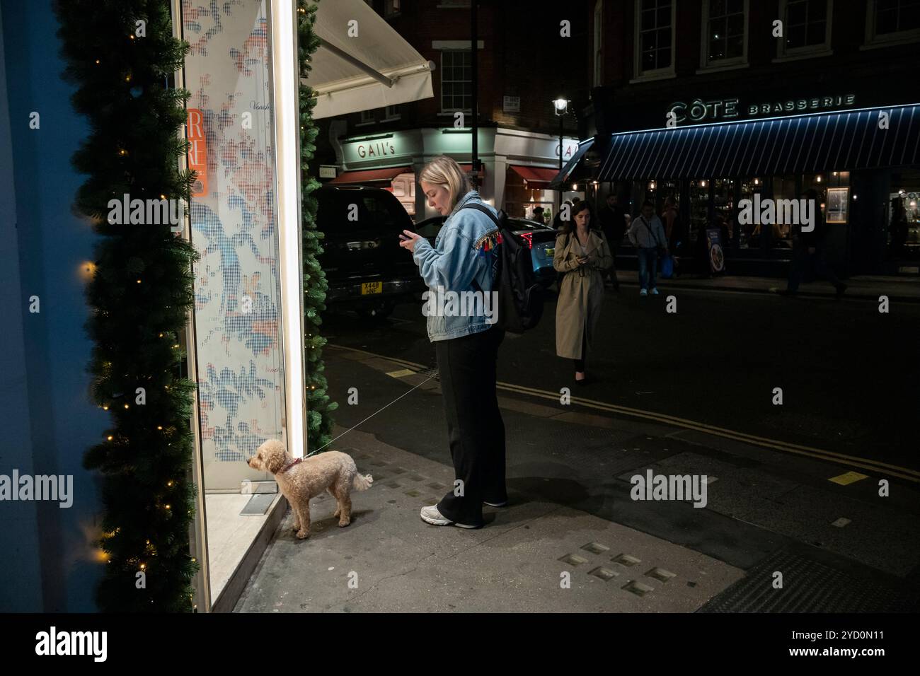 Ein Hund und sein Besitzer warten geduldig vor einem Geschäft in der Wardour Street in Soho, Londons West End, England, Großbritannien Stockfoto