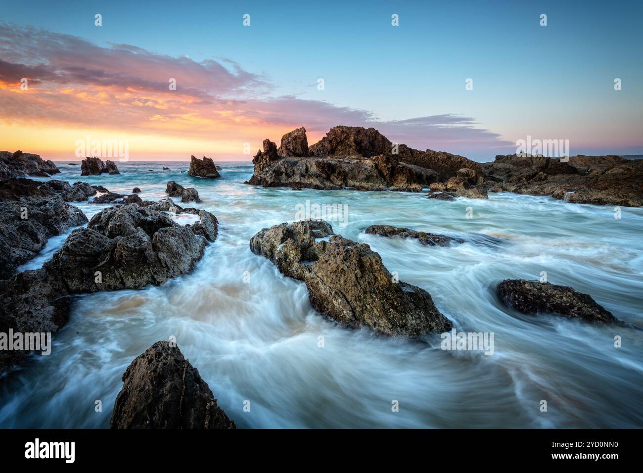 Am frühen Morgen weht die Wellen um zerklüftete Felsen an der Küste von Narooma Stockfoto