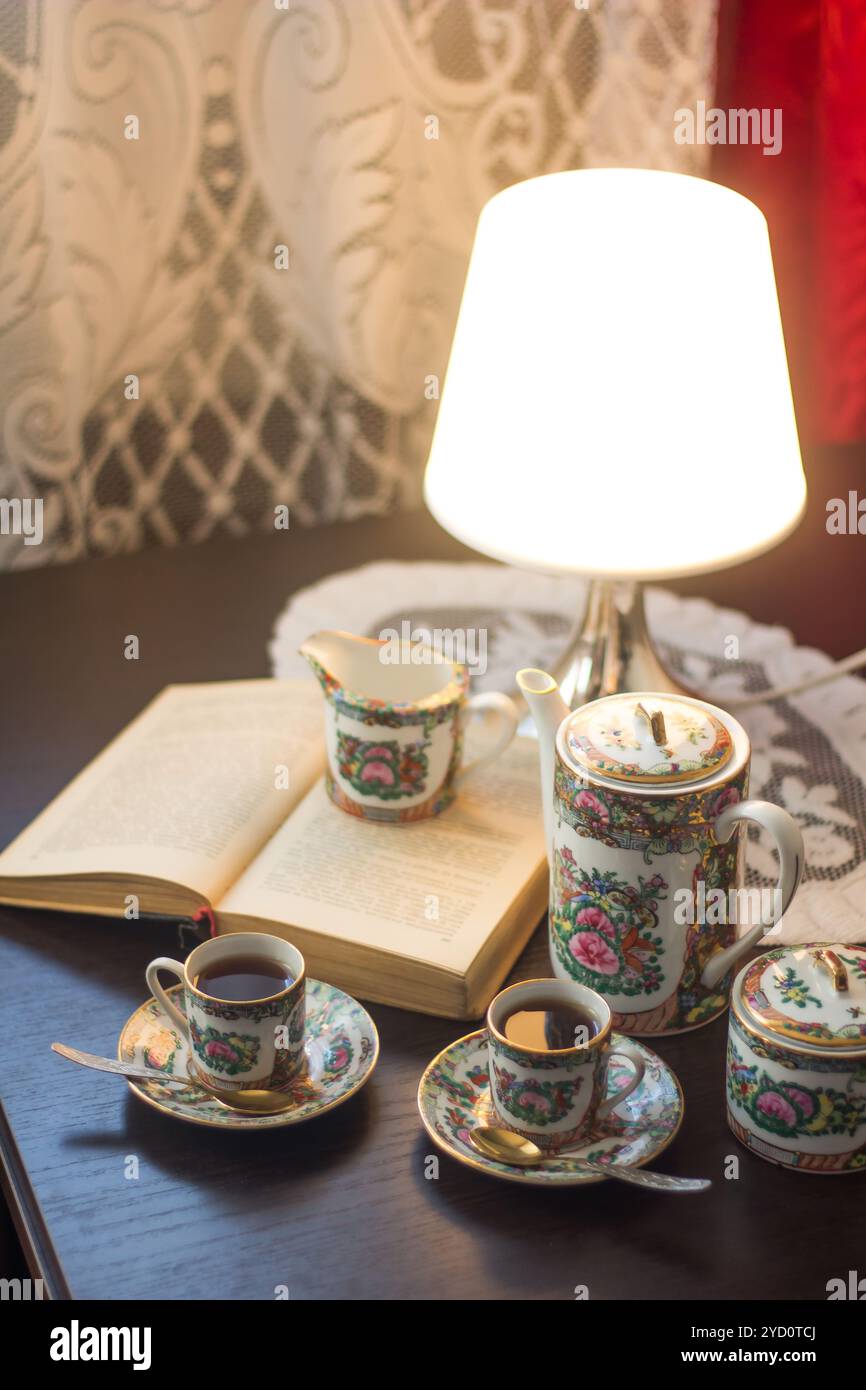 Becher mit Kaffee auf einem Tisch mit einer Lampe und ein Buch. Tassen Kaffee. Heißes Getränk. Spirituellen treffen. Koffe Pause Stockfoto