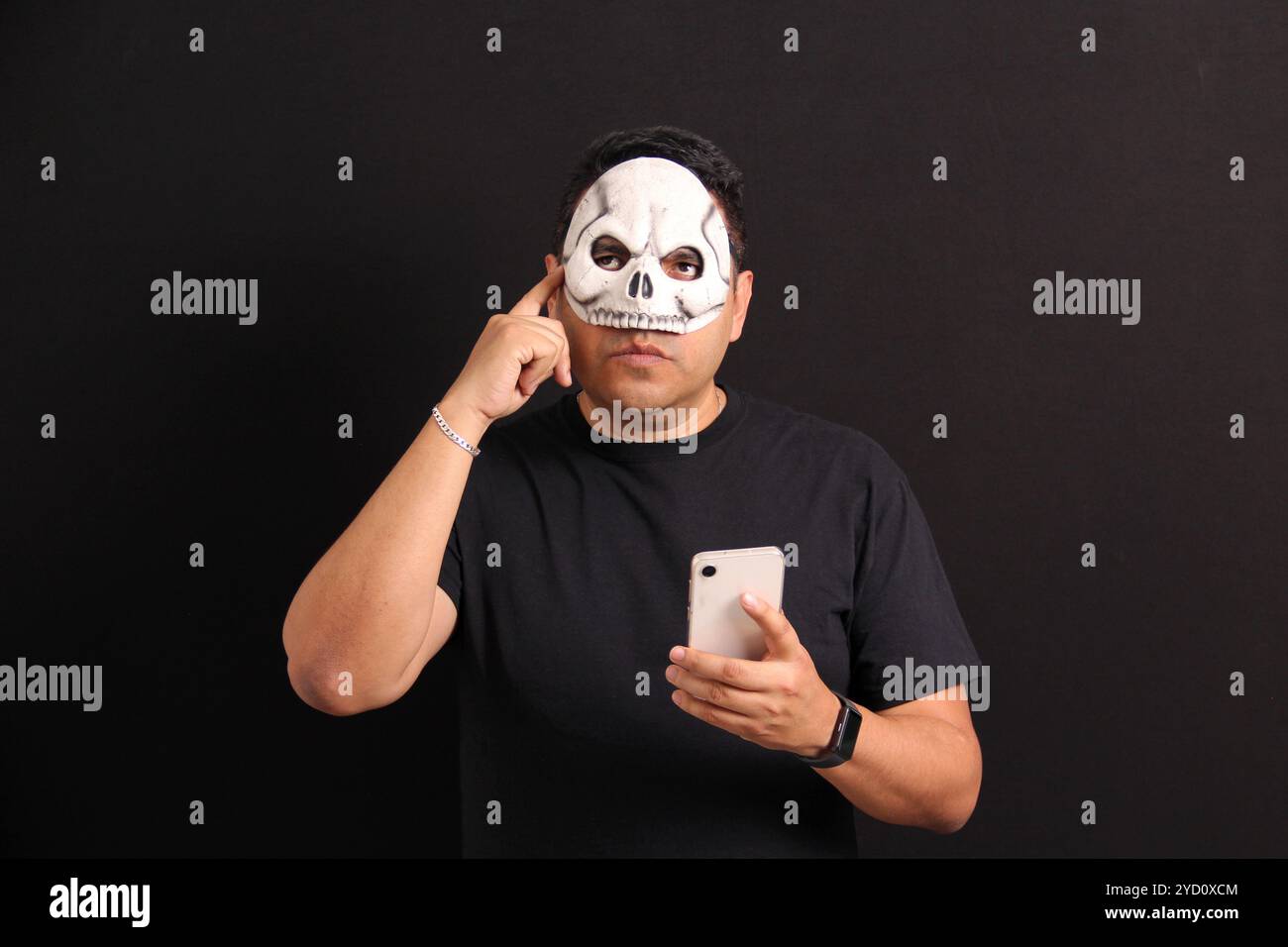 Mexikanischer Erwachsener mit Schädelmaske nutzt sein Handy, um die "Day of the Dead"-Aktionen und Rabatte in Mexiko zu nutzen Stockfoto