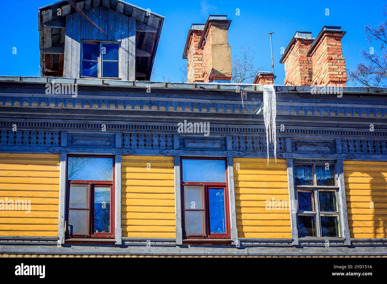 Eiszapfen hängen vom Dach des Hauses. Gefrorenes Wasser. Wasser tropft vom Dach. Stockfoto