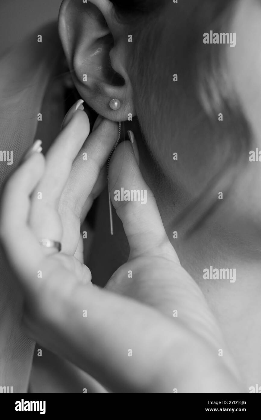 Elegante Nahaufnahme einer Frau, die einen Perlenohrring in Schwarz und weiß verstellt. Stockfoto