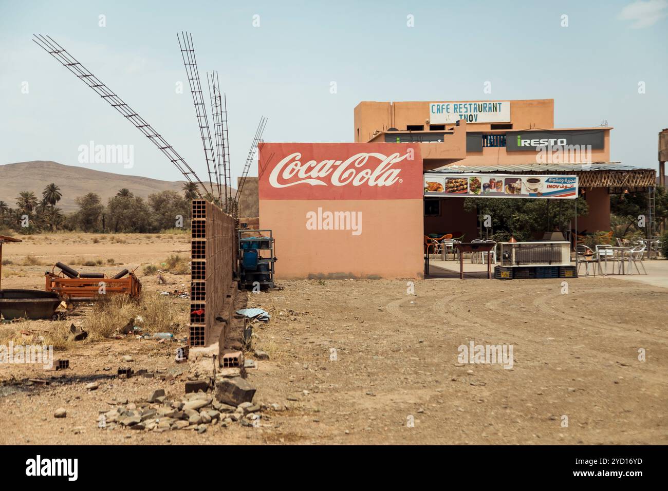 In einem sonnenverwöhnten marokkanischen Ambiente befindet sich neben einem alkoholfreien Getränk ein Café, das die trockene Landschaft und die unverwechselbare Architektur der Region hervorhebt Stockfoto