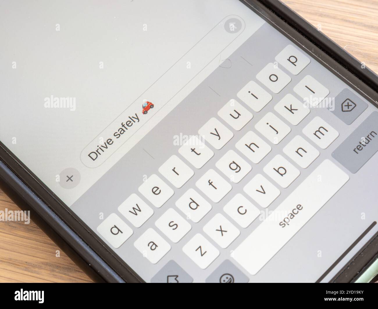 Eine Nahansicht eines Mobiltelefonbildschirms, der eine Textnachricht in einem Gespräch mit Emoji mit der Aufschrift „sicher fahren“ anzeigt Stockfoto