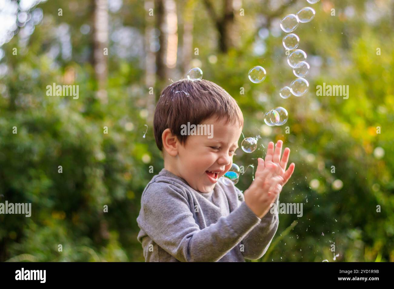 Ein Junge auf der Straße fängt Seifenblasen. Glückliche Kindheit. Kinderspiele. Stockfoto