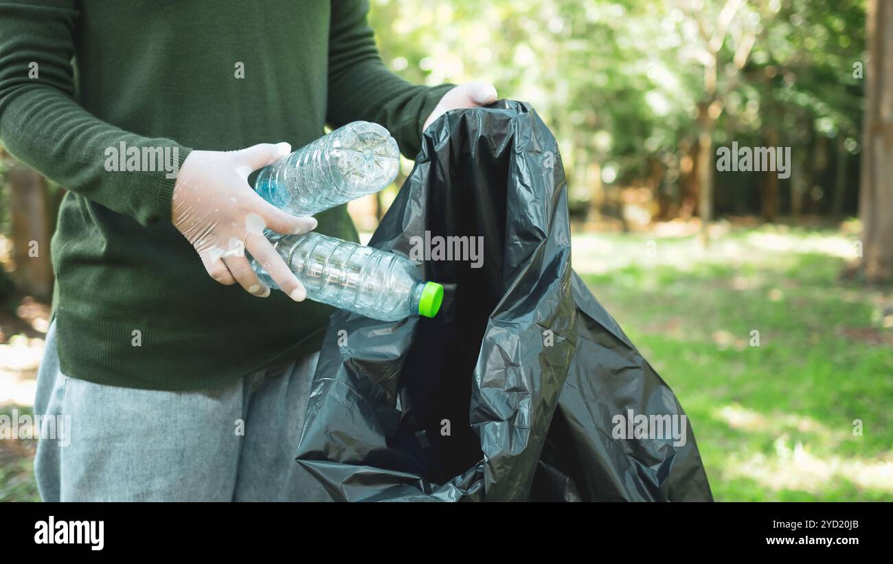Frauen engagierter Freiwilliger nehmen an einer Umweltreinigungsaktion in einem Park Teil. Frau trägt Handschuhe und hält große schwarze Taschen. Frau Stockfoto