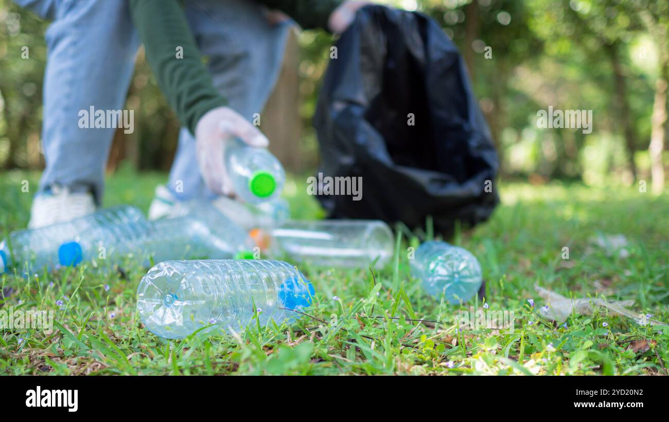 Frauen engagierter Freiwilliger nehmen an einer Umweltreinigungsaktion in einem Park Teil. Frau trägt Handschuhe und hält große schwarze Taschen. Frau Stockfoto